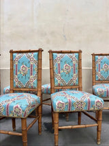 Three matching upholstered dining chairs with bamboo-style frames and turquoise floral patterned fabric, photographed against a plain beige wall. Callista Home