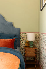 Bedroom corner with floral wallpaper, wooden nightstand, and decorative items.