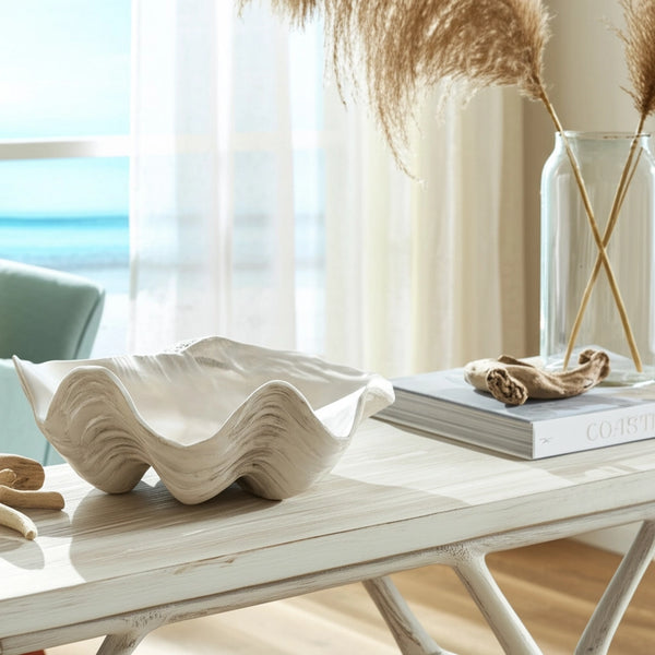 Decorative shell on a table with a blurred indoor background, Decorative ivory and tan resin bowl with sculptural coastal seashell design Callista Home
