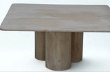 A modern stone dining table with a rectangular top and three cylindrical pedestal legs, crafted from a light beige travertine or limestone.  Callista Home