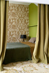 Bedroom with patterned wallpaper, green walls, and draped curtains.