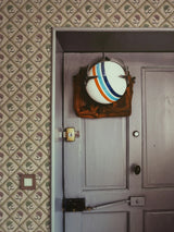 Decorative wall light fixture on a door with patterned wallpaper