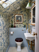 Bathroom with patterned wallpaper, toilet, sink, and decorative elements. Jaipur 57B blue French wallpaper by Antoinette Poisson featuring a historic domino paper pattern with an ultra-matte finish. Callista Home