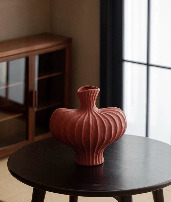 Pink ribbed vase on a dark wooden table with a blurred background Callista Home
