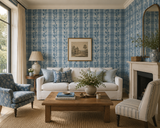 A styled living room featuring blue and white plaid wallpaper as the primary product, shown on the accent wall behind a white sofa, wooden coffee table, blue floral armchair, and cream striped chair.