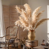 Decorative vase with pampas grass on a wooden barrel in a room with a chair and curtains. Callista Home