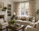 A styled living room featuring floral patterned curtains, a cream sofa with matching accent pillows, a striped armchair, and a wooden coffee table. Callista Home