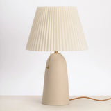 Handcrafted peach ceramic pleat table lamp with a rust pleated shade and brass pull chain.