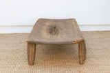Wooden footstool on a textured surface with a white wall background
