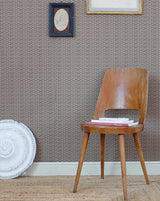 Wooden chair with a pink cushion against a textured wall with framed pictures. Osier Wallpaper Panel 18B by Antoinette Poisson featuring a classic woven basket-inspired French heritage pattern.