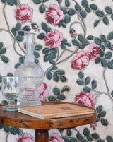 Decorative table with a glass vase and candle against a floral wallpaper background