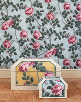 Decorative boxes with floral design on a wooden surface and floral wallpaper background