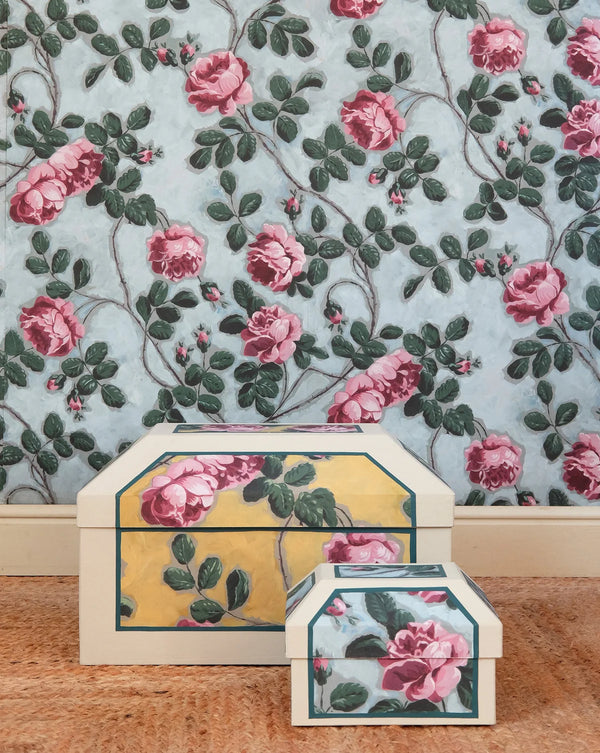 Decorative boxes with floral design on a wooden surface and floral wallpaper background