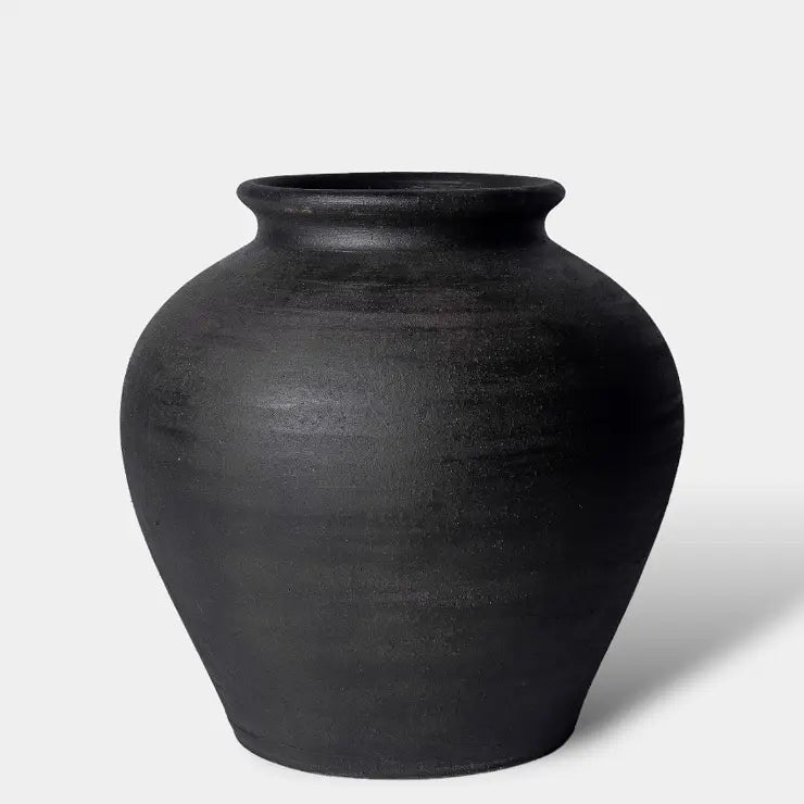 A matte black ceramic vase with a rounded body and a flared rim, photographed on a clean light gray background.