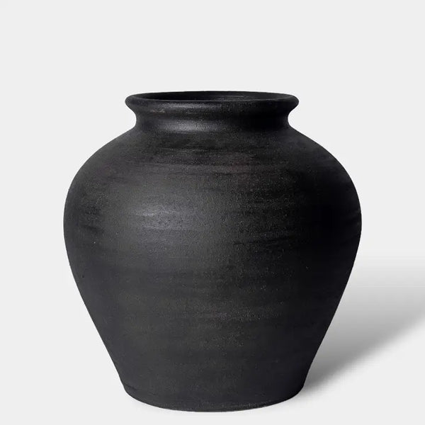 A matte black ceramic vase with a rounded body and a flared rim, photographed on a clean light gray background.