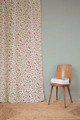 Floral curtain with a wooden chair and stack of books against a light green wall. Jardin d'Oeillets 87A French floral linen cotton fabric Callista Home