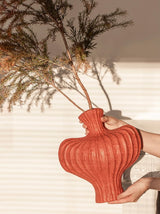 Person holding a textured red vase with dried plants against a neutral background Callista Home