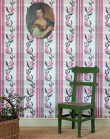 Pink and white floral wallpaper with vertical stripes and a vintage-style portrait hanging on the wall above a green wooden chair.