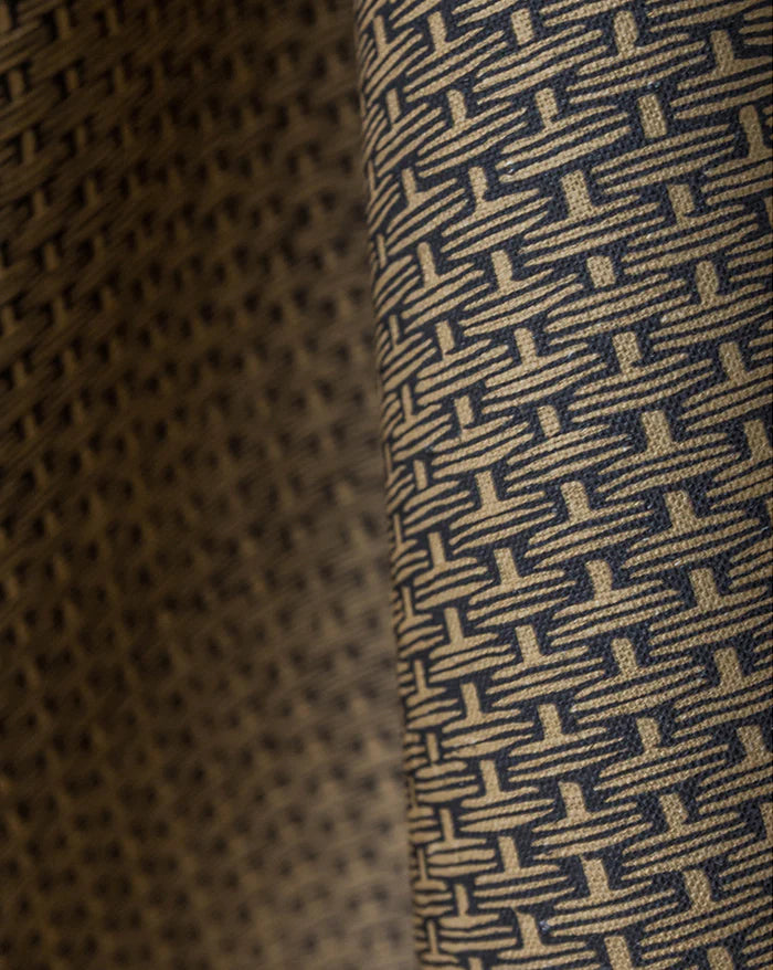 Close-up of a woven fabric with a repeating geometric basketweave pattern in beige and dark navy blue. Osier 18A geometric French linen fabric by Antoinette Poisson allista Home