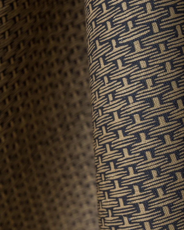 Close-up of a woven fabric with a repeating geometric basketweave pattern in beige and dark navy blue. Osier 18A geometric French linen fabric by Antoinette Poisson allista Home