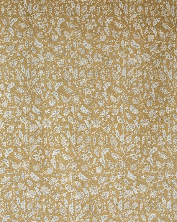 A close-up of a woven fabric or wallpaper pattern featuring a repeating white floral and leaf motif on a warm mustard yellow background. Callista Home